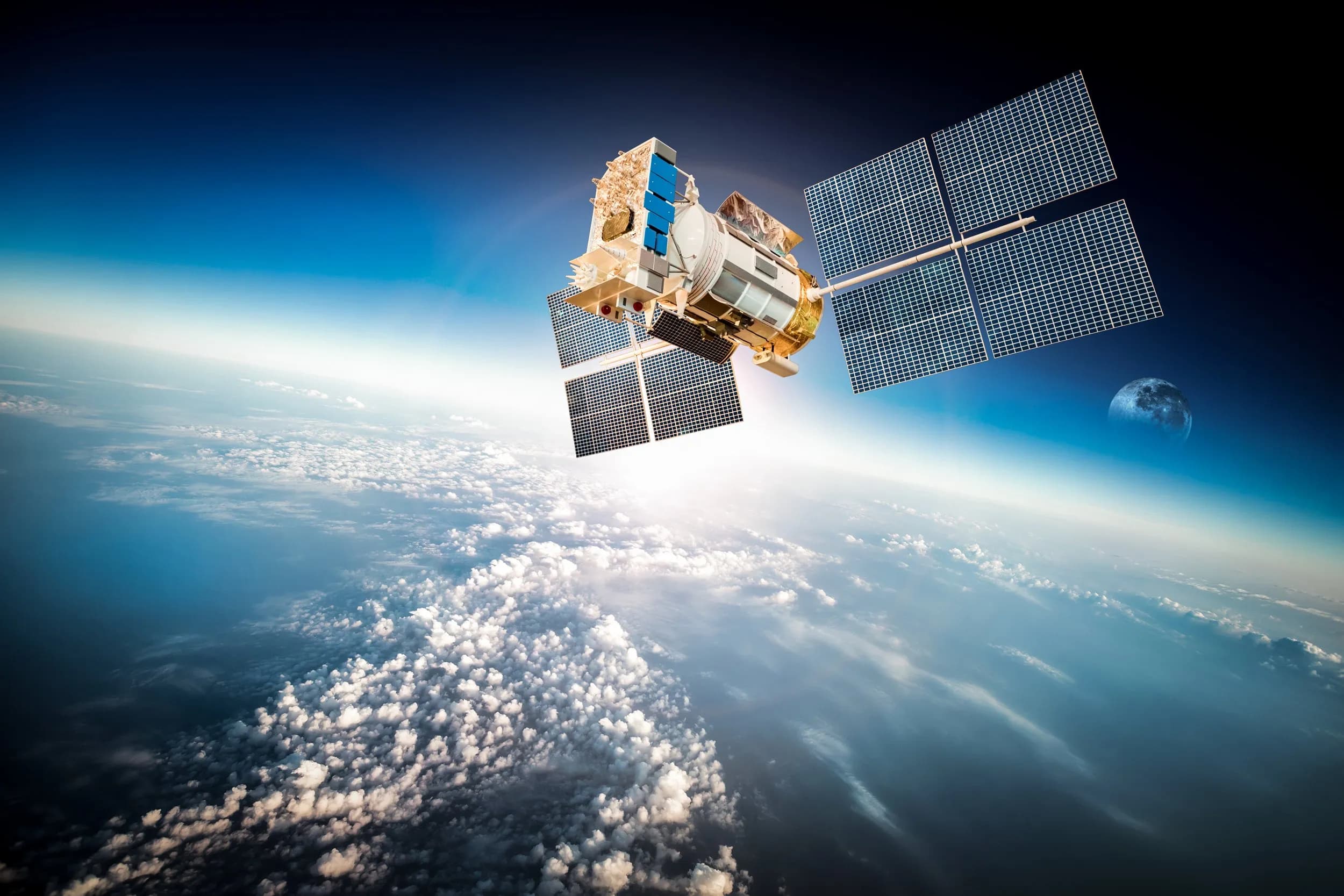 Communications satellite in low Earth orbit above cloud cover, representing space and satcomms electronics applications for PCB manufacturing