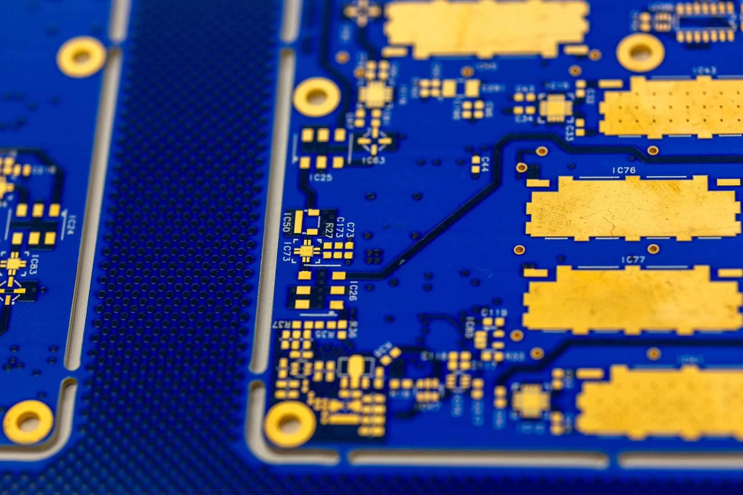 A detailed close-up of a blue printed circuit board showing trace routing and integrated circuit component pads.