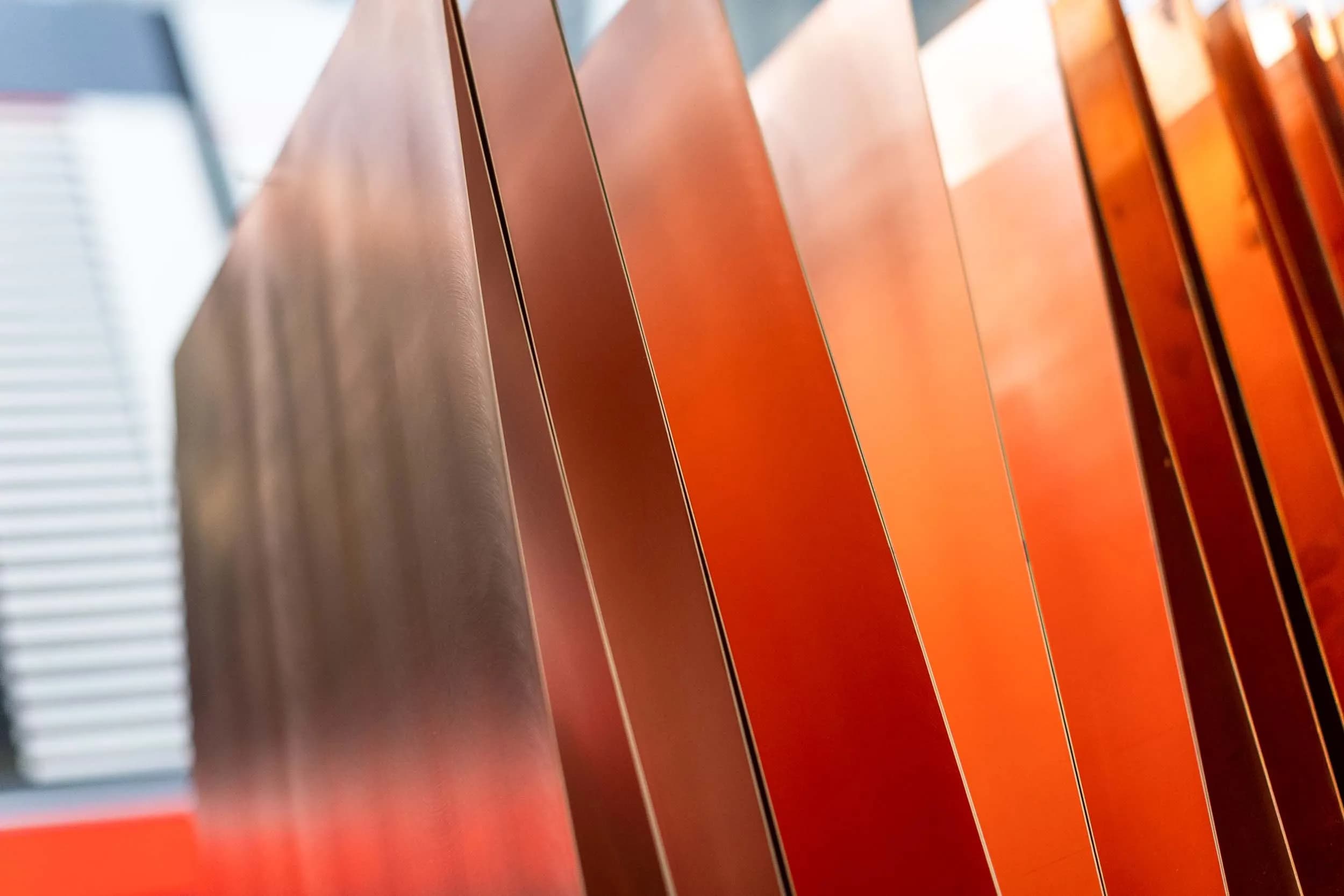 Macro close-up of polished copper-clad laminate panels standing vertically in a storage rack, showing reflective copper surfaces and dielectric substrate edges at Exception PCB.