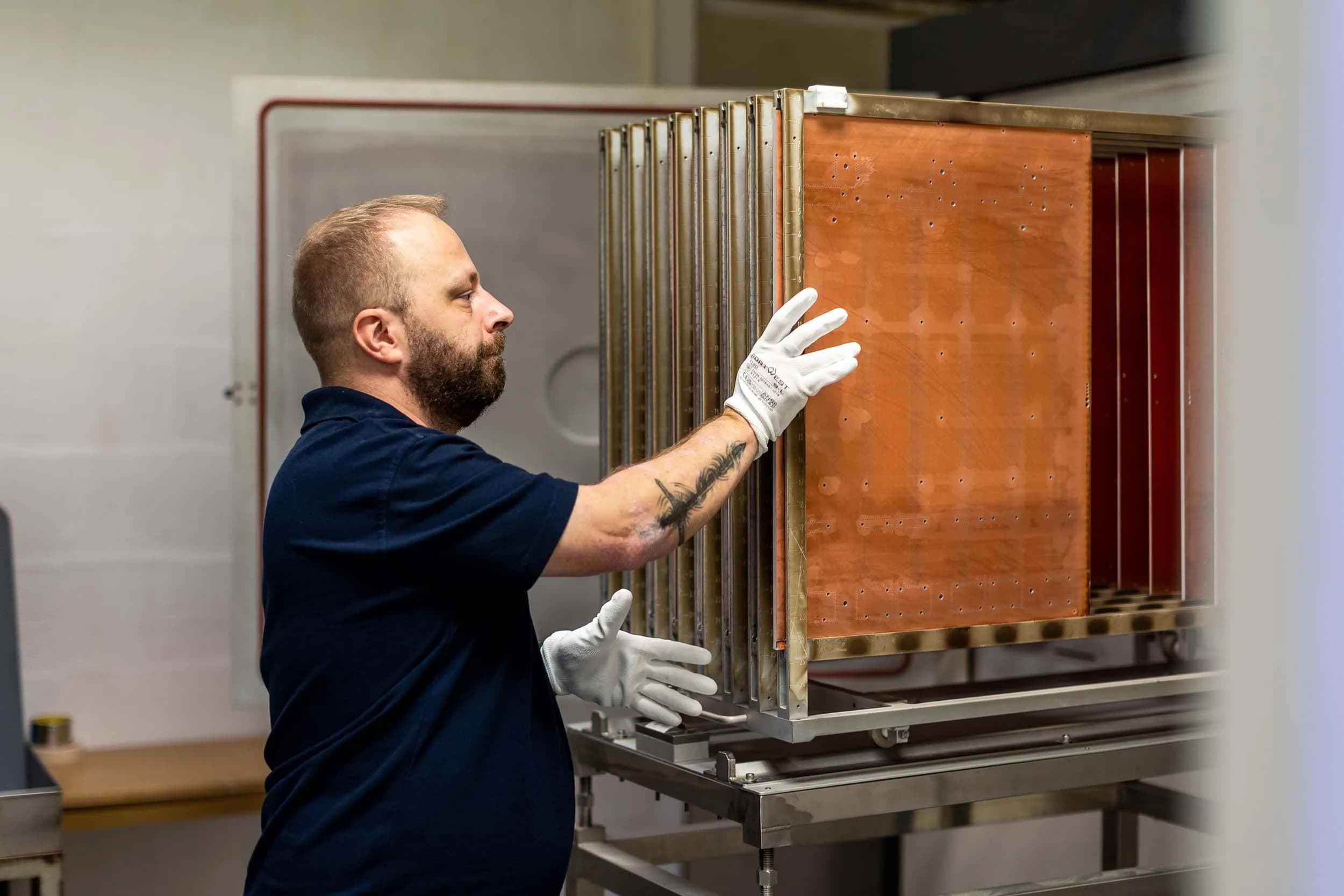Exception PCB technician loading copper-clad panels into a vertical electroplating rack on a stainless steel processing trolley.