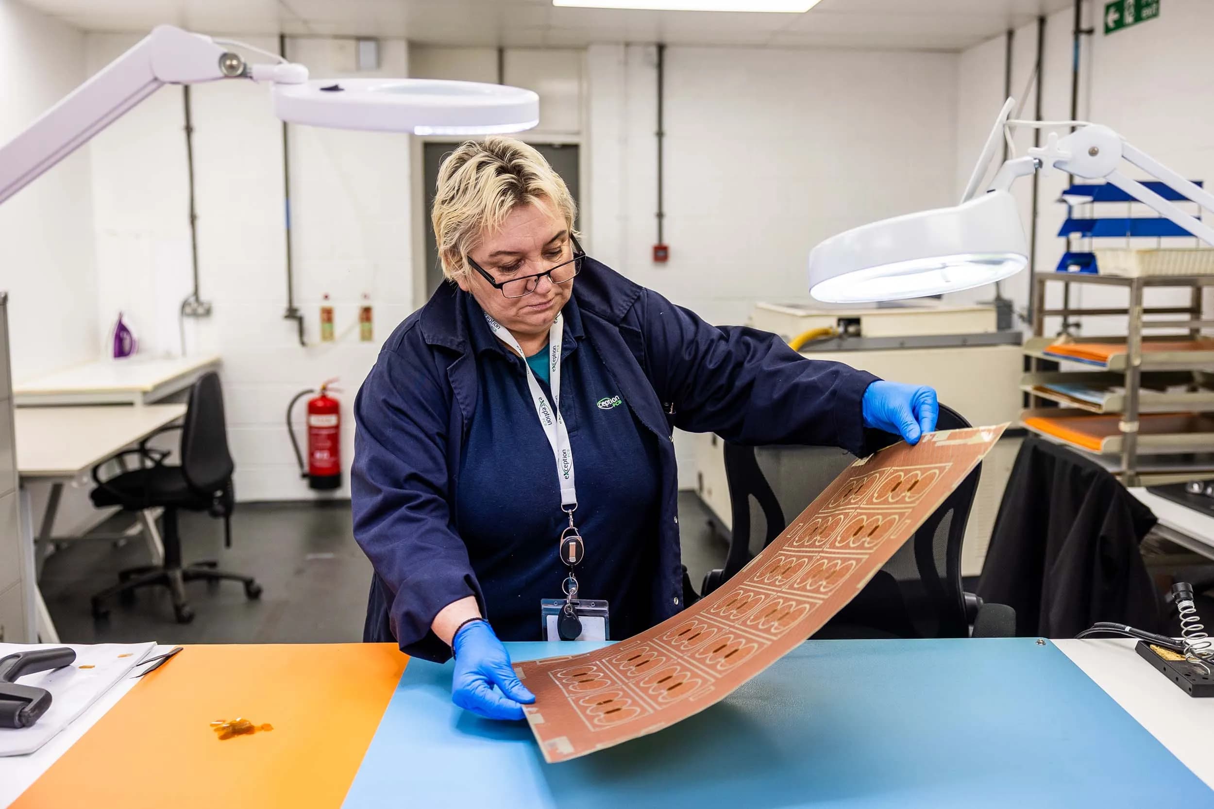 An Exception PCB technician holding up a large, flexible copper-clad multi-layer board panel to demonstrate its flexibility and structural pattern.