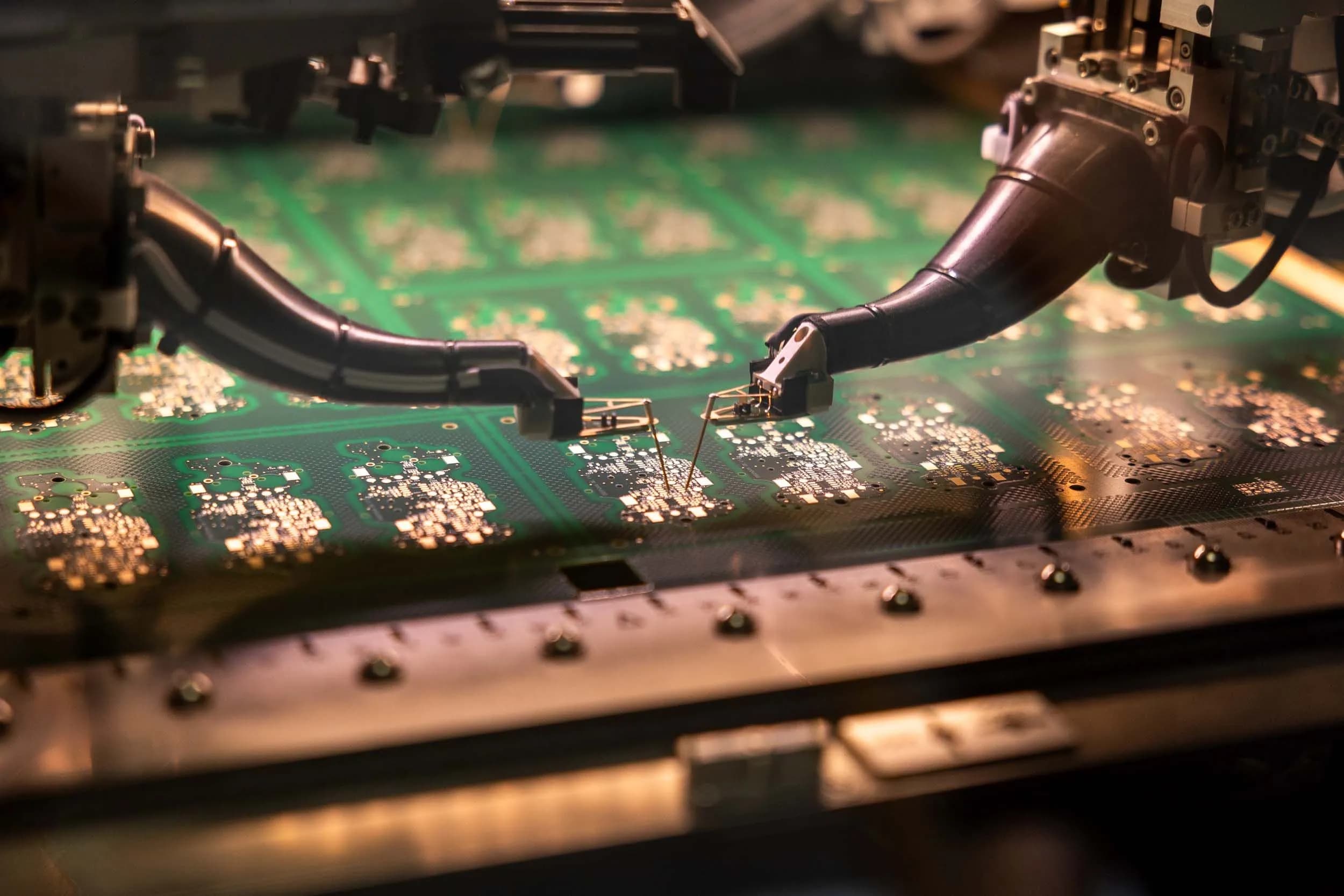 Close-up of flying probe test heads making electrical contact with a multilayer PCB during automated testing at Exception PCB