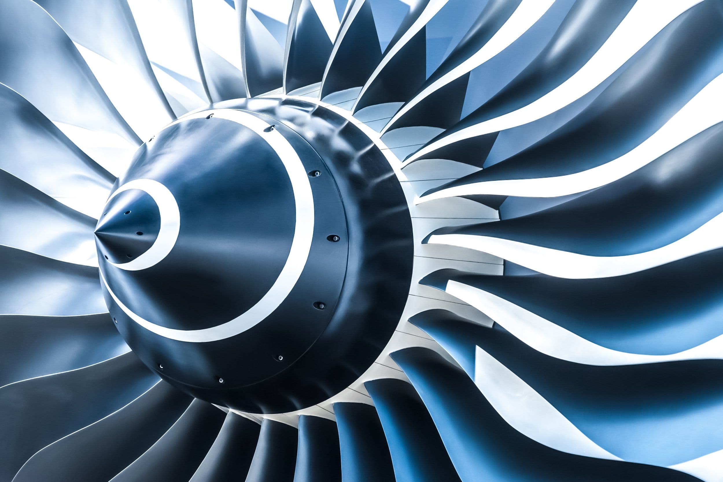 Detailed close-up of a high-precision jet engine intake turbine fan in metallic blue and silver tones.