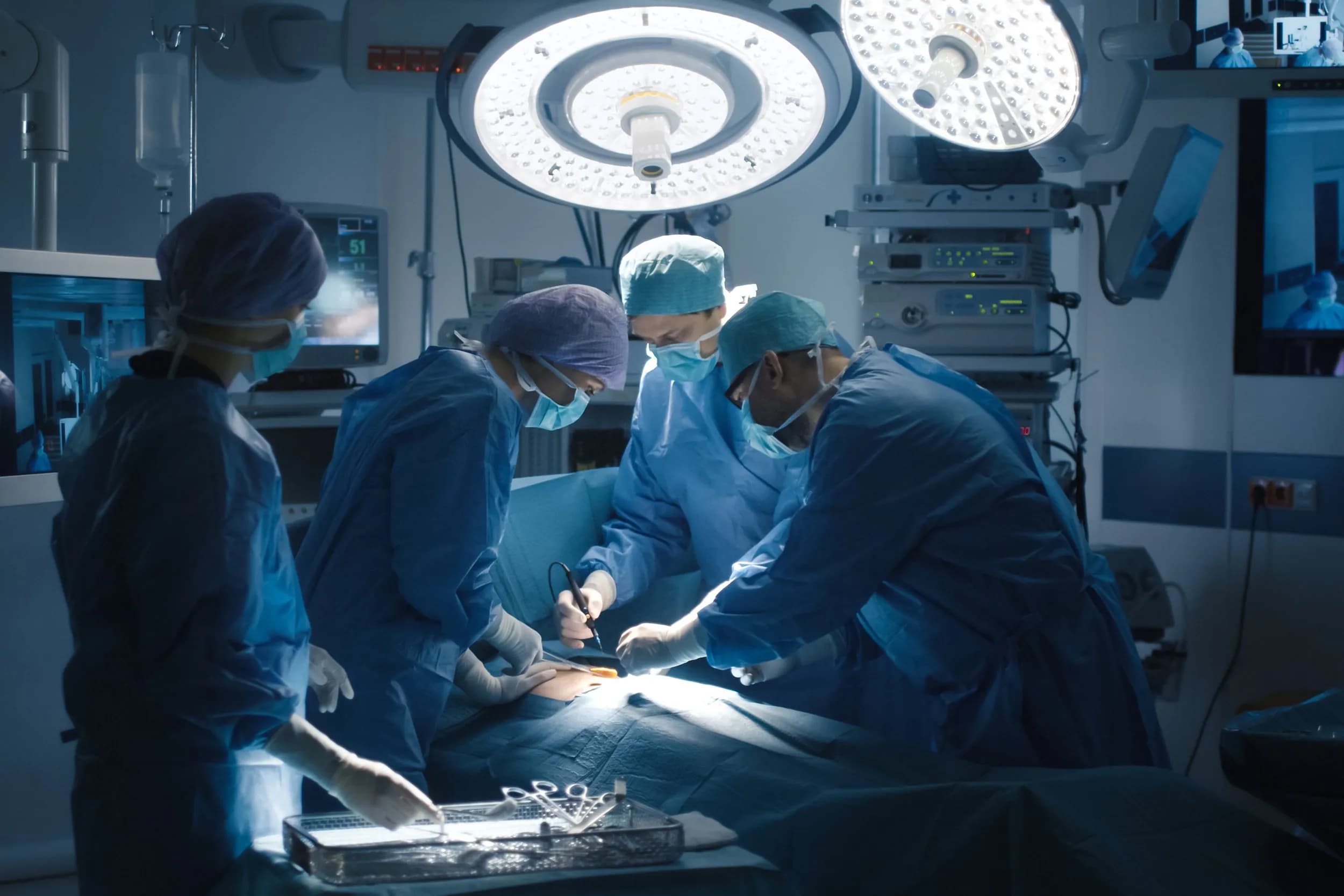 A surgical team performing an operation under overhead lights in a high-tech operating theatre.
