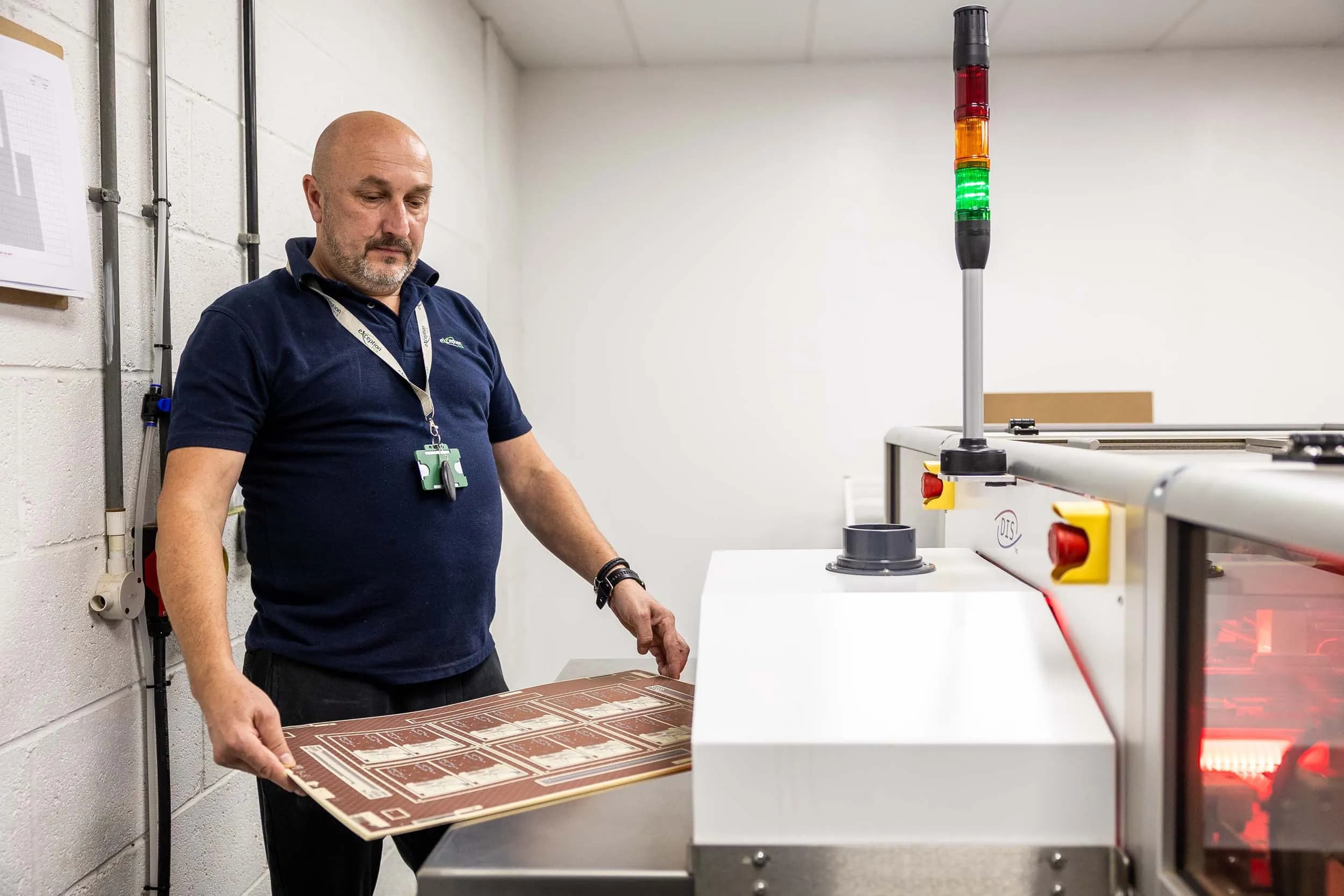 Exception PCB operator loading a circuit board inner layer panel into a specialised automated lamination processing cell.