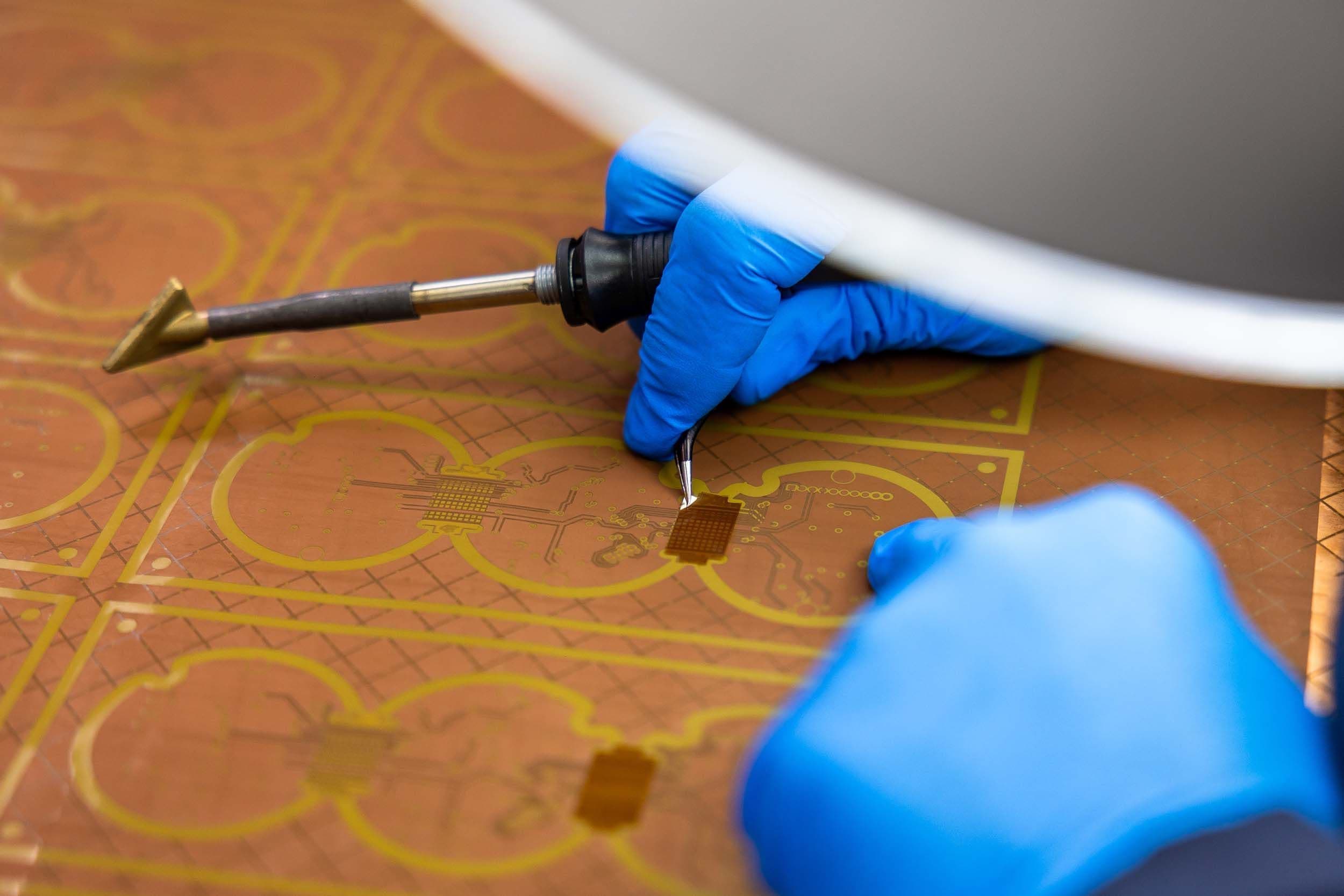 Exception PCB technician carrying out precision manual PCB rework, showing the hands-on technical skill involved in high-technology PCB manufacture.