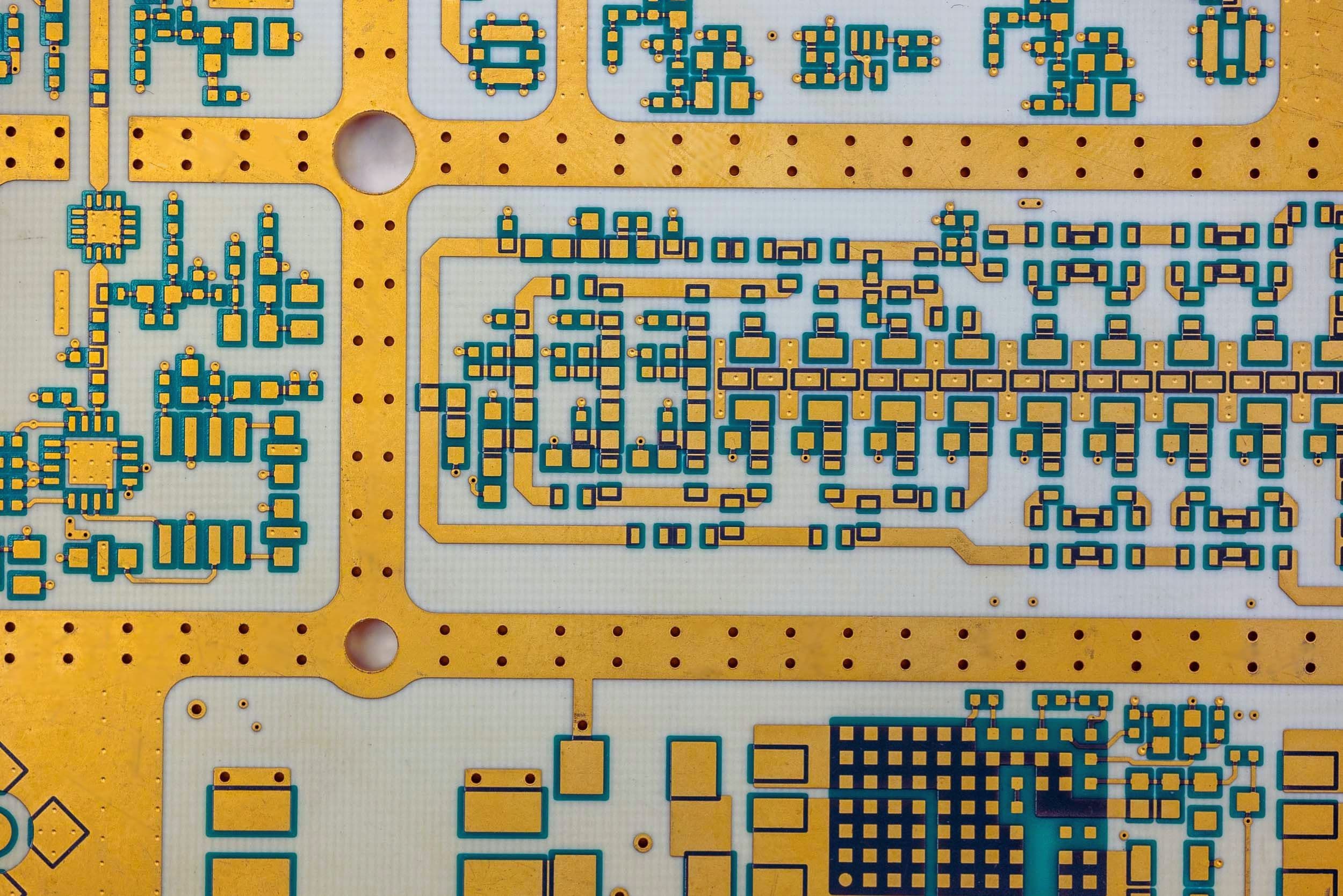 Macro close-up of ENIG gold-plated pads and precision circuit trace routing on a white substrate RF PCB, showing the surface finish quality and high-density layout of Exception PCB's RF manufacturing capability.