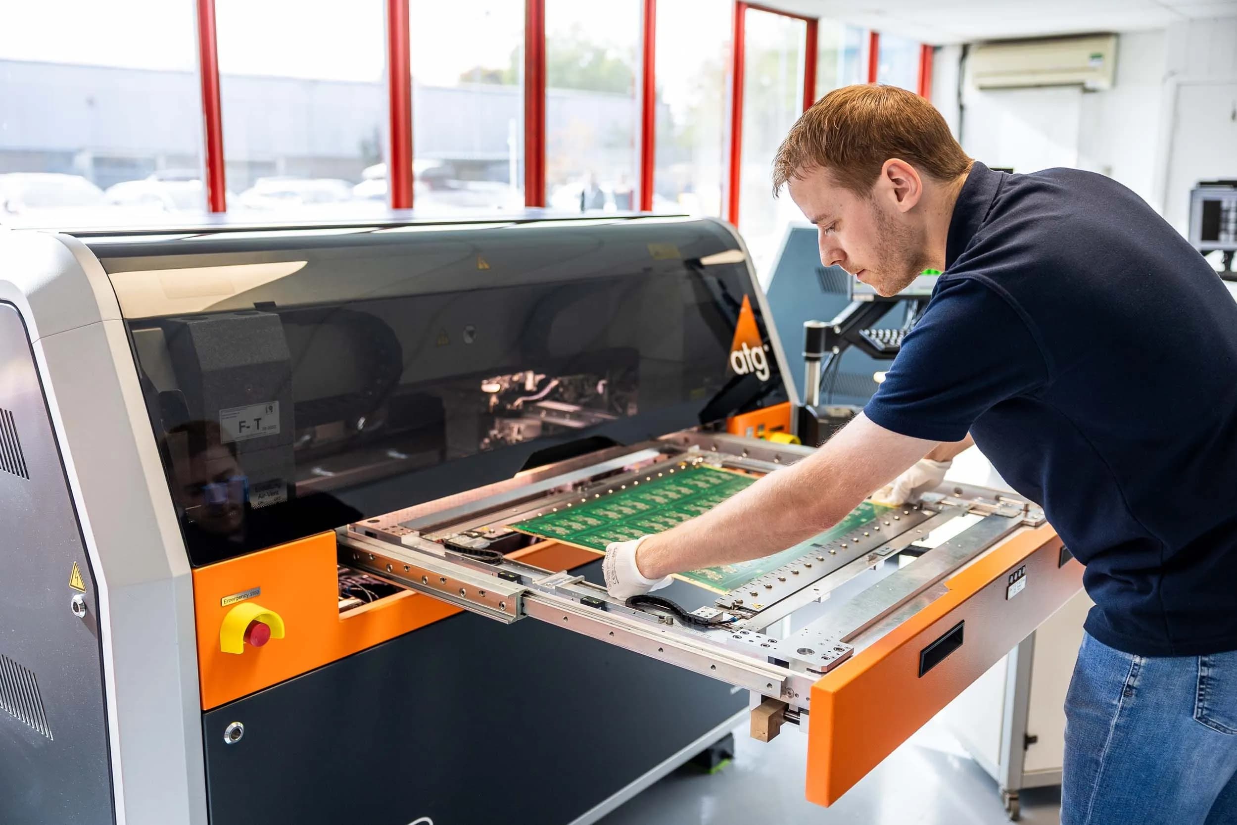 An Exception PCB technician loading a printed circuit board panel into an ATG flying probe electrical test system.