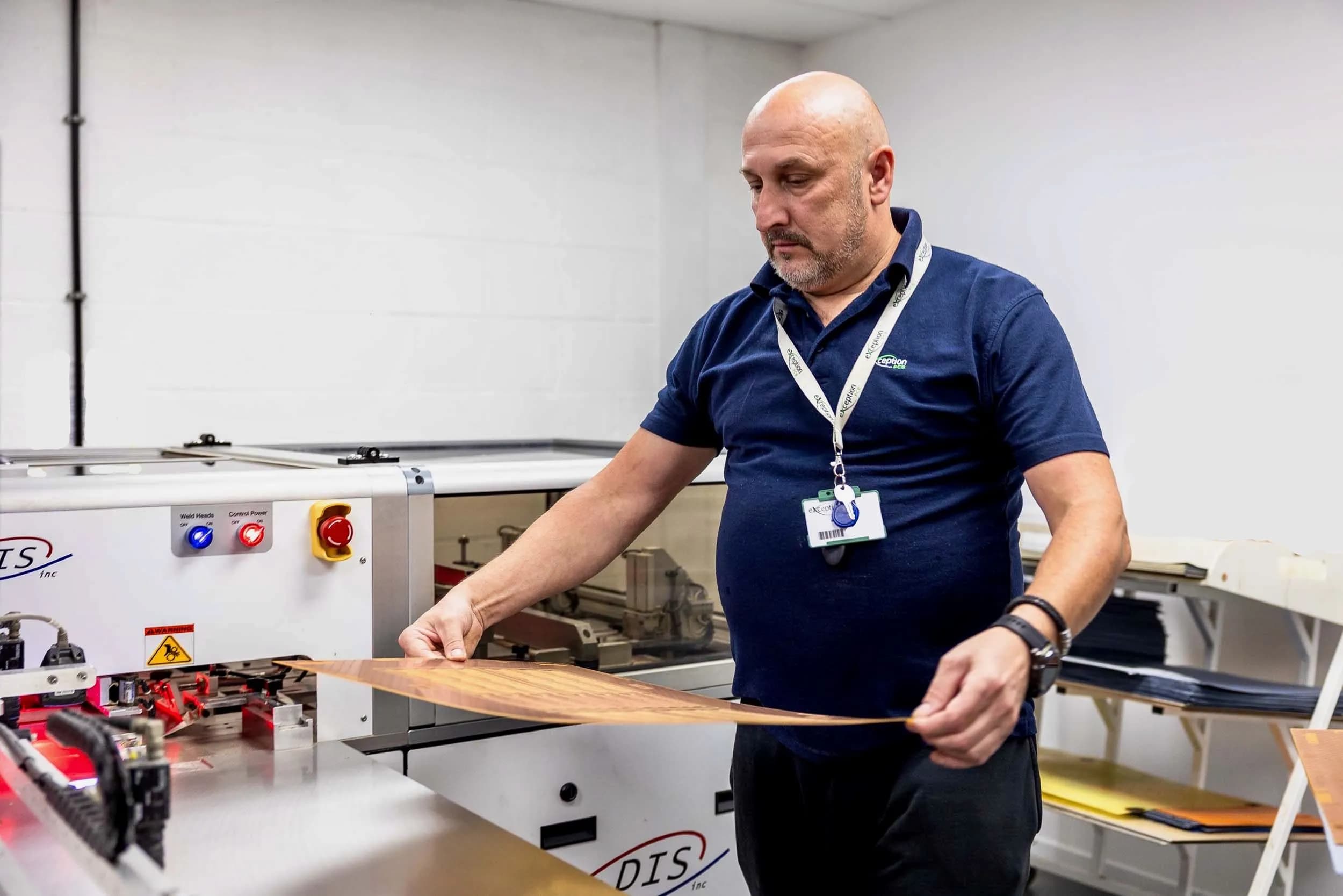 Exception PCB technician loading an intricate brown inner layer panel into a multilayer bonding registration system.