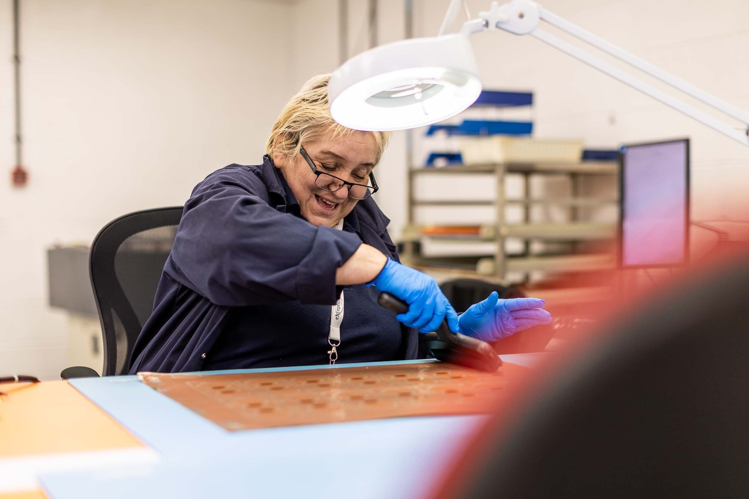 Exception PCB technician carrying out manual PCB rework, showing skilled hands-on manufacturing in a supportive production environment.