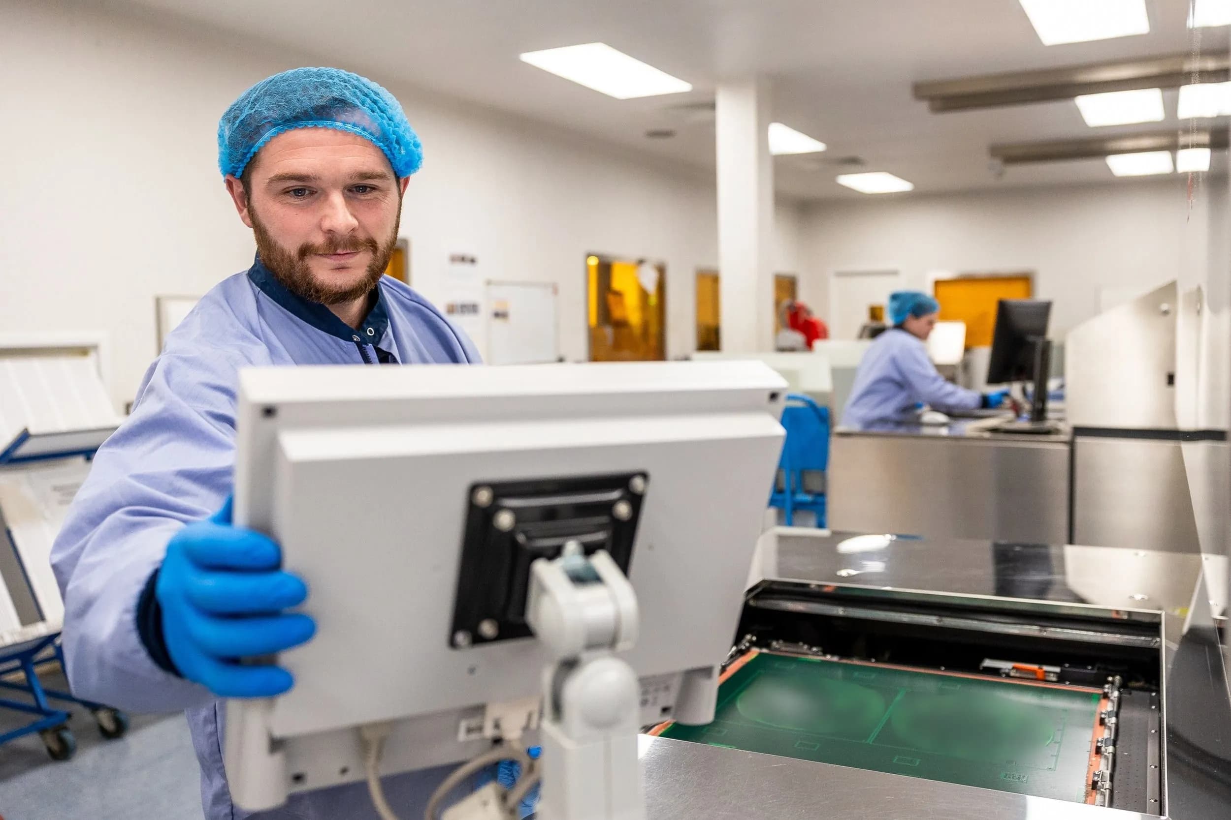 Exception PCB technician operating specialist PCB manufacturing equipment with printed circuit board panels in production.