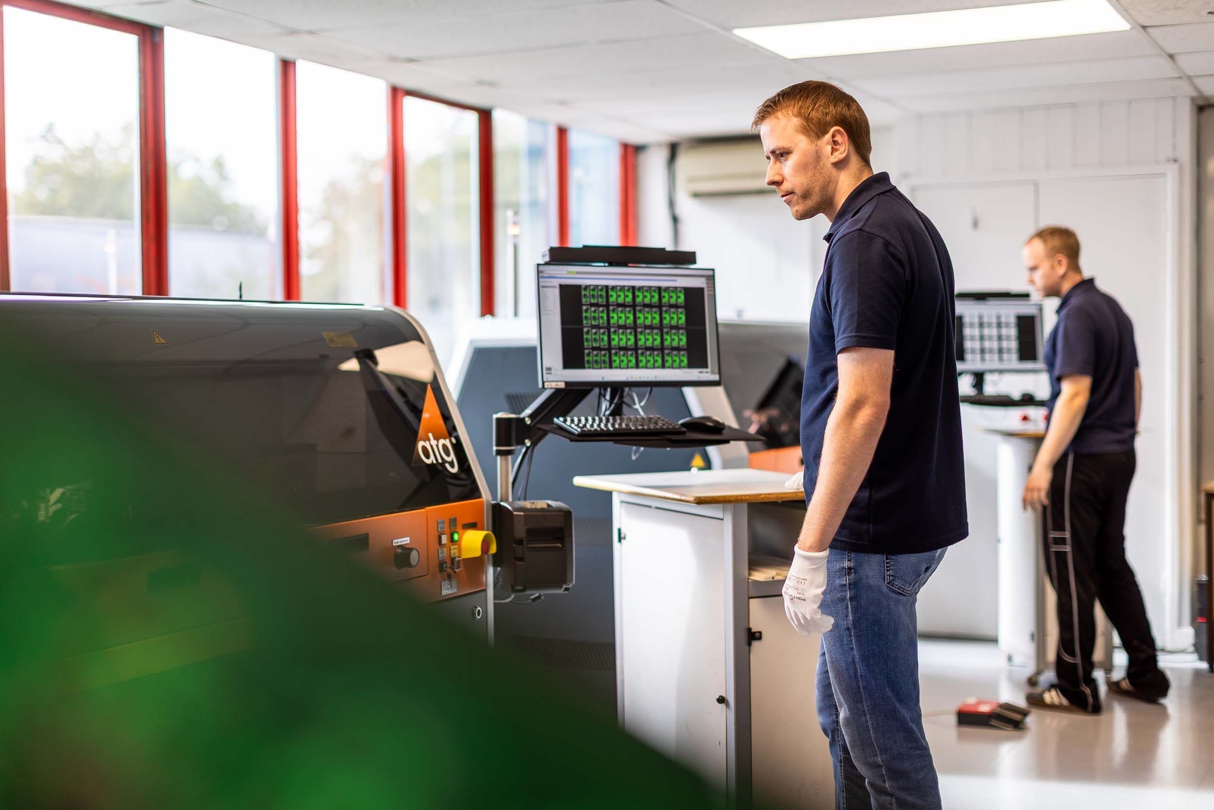 Two Exception PCB technicians working at ATG electrical test machines in a dedicated PCB test room.