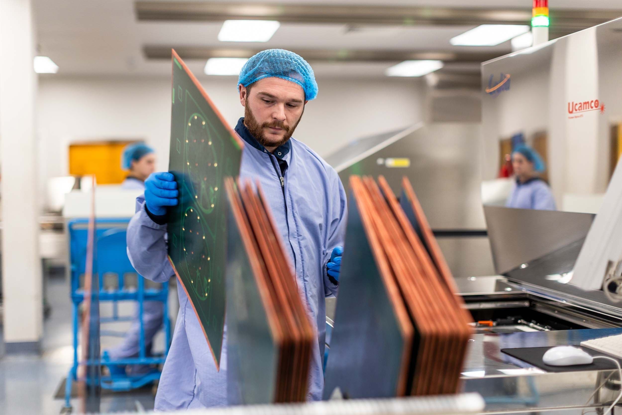 PCB manufacturing operator handling large printed circuit board panels during inspection at Exception PCB’s UK facility.