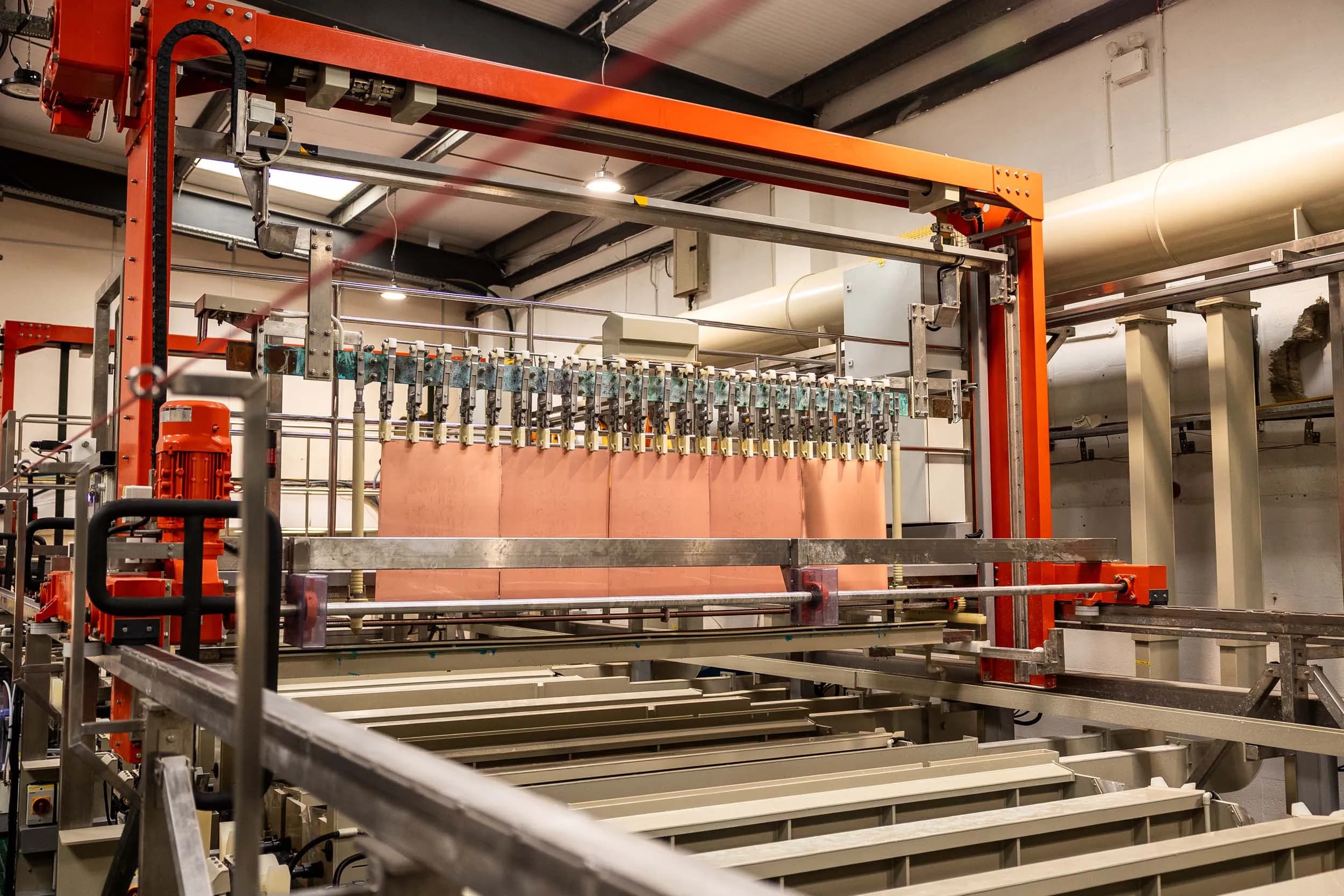 Wide landscape view of an automated electrochemical processing line inside the manufacturing plant.